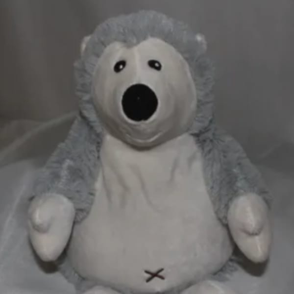 Gray and white plush teddy bear with a stitched mouth and open black nose