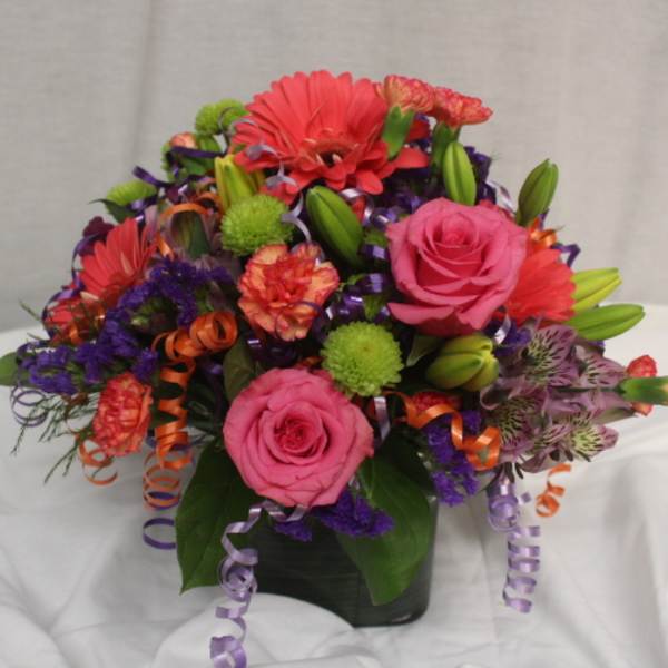 Colorful bouquet with pink roses, gerbera daisies, and lilies in a dark vase