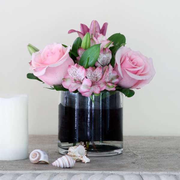 Pink roses and lilies arranged in a clear glass vase