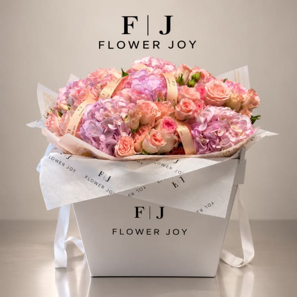 Pink and peach roses with lavender hydrangeas in a white gift box