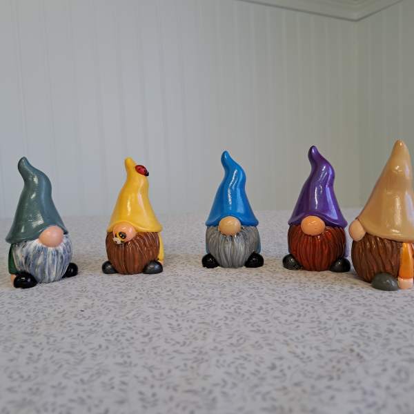 Five small painted gnome figurines lined up on a tabletop