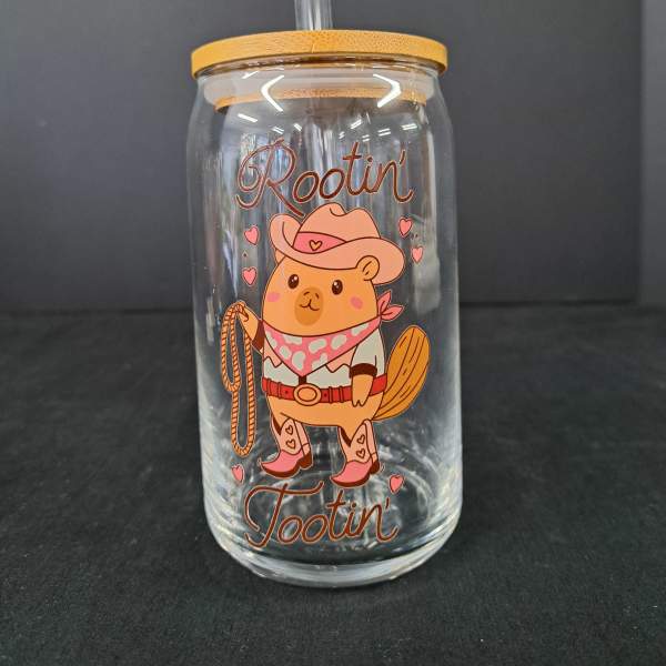 Clear glass tumbler with a straw and cowboy bear graphic