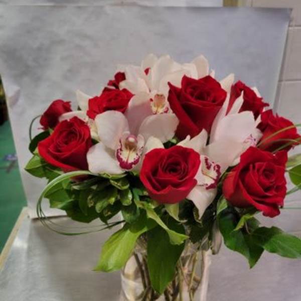 Red roses and white orchids arranged in a clear glass vase