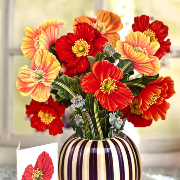 Bouquet of red and orange poppy-like flowers in a striped vase with a card