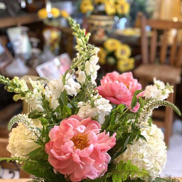 Pink peonies and white flowers arranged in a glass vase