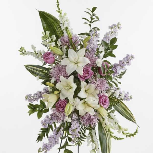Standing floral spray with white lilies and pink roses on a black easel