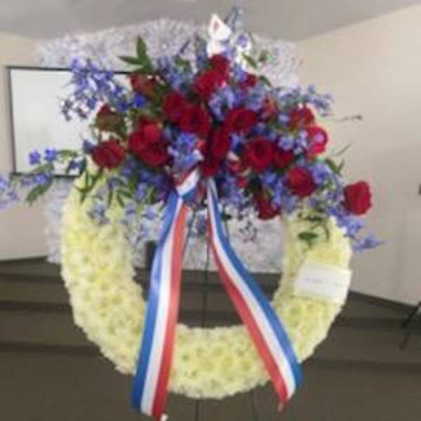 Red and blue floral wreath on an easel with ribbon streamers