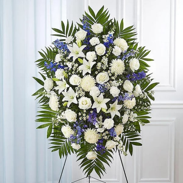 Standing funeral spray of white and blue flowers on an easel