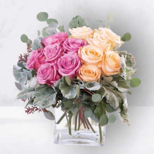 Pink and peach roses in a clear square vase