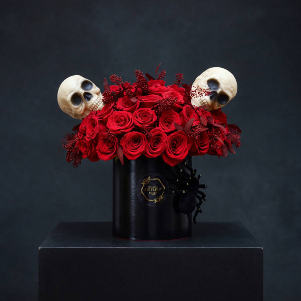Red roses in a black hatbox with two skull decorations