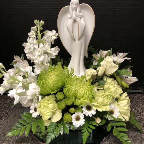White floral arrangement with a praying angel statue in the center