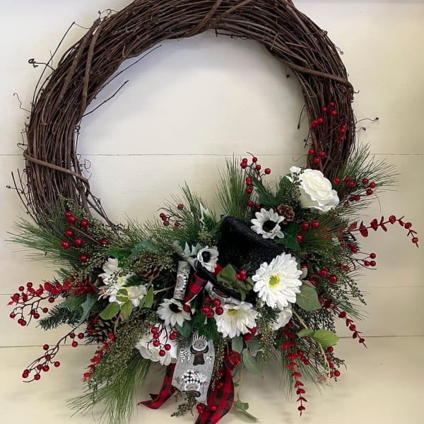 Holiday wreath with white flowers, red berries, and a plaid ribbon