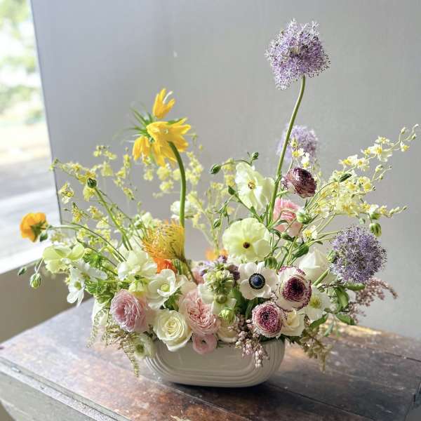 Mixed pastel flowers in a white ceramic bowl vase
