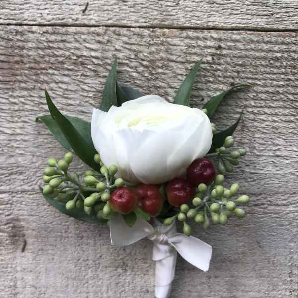 White boutonniere with red berries and green leaves