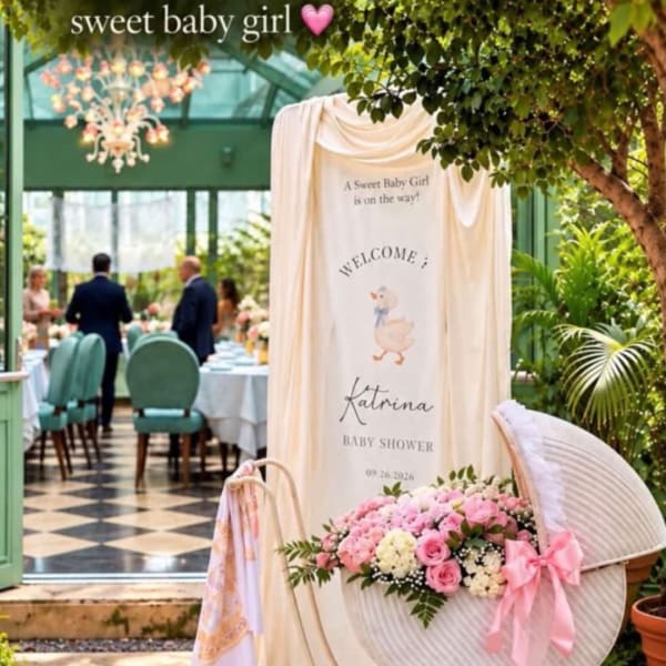 Baby shower display with pink flowers, draped fabric, and a welcome sign