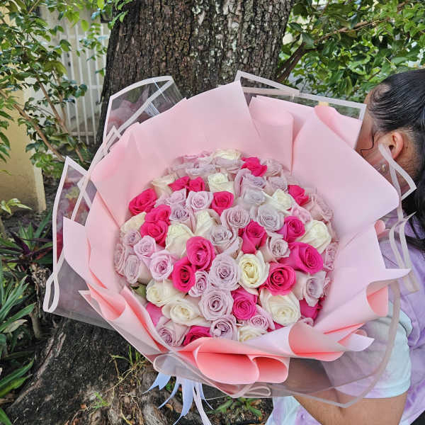 Large bouquet of pink, lavender, and white roses wrapped in pink paper