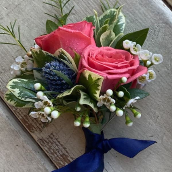 Pink rose boutonniere with white filler flowers and a blue ribbon