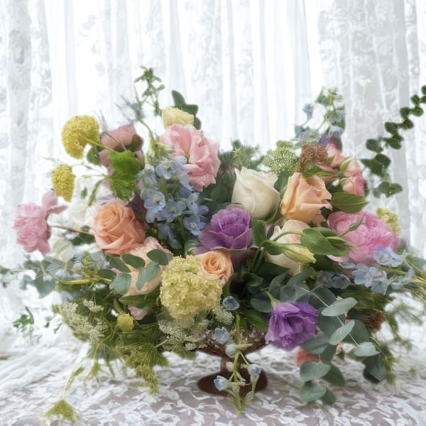 Mixed pastel flower arrangement in a low pedestal vase