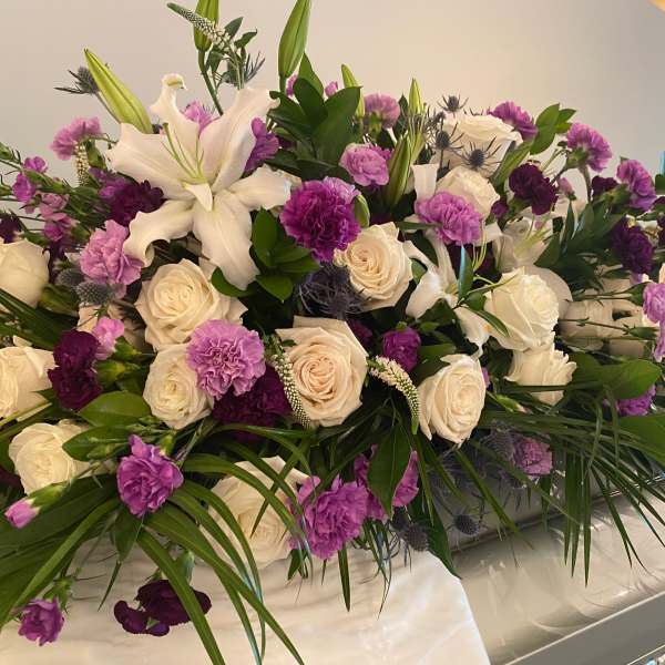 Large white and purple floral casket spray with roses and lilies