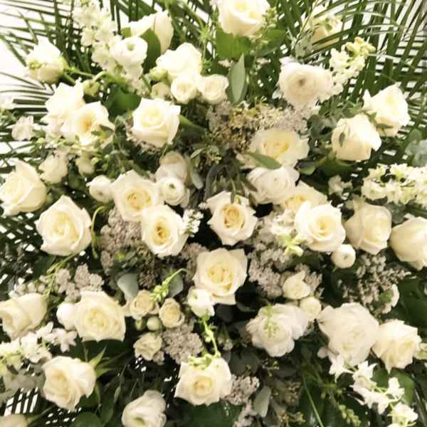 Large white rose funeral spray with greenery