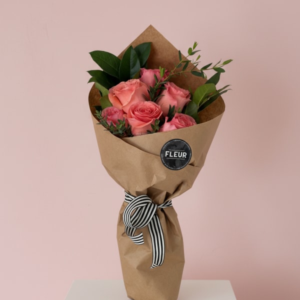 Bouquet of pink roses wrapped in brown paper with a striped ribbon