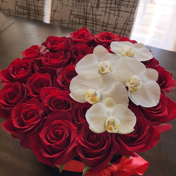 Red roses arranged with white orchids in a round bouquet