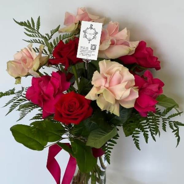 Bouquet of red and blush roses in a glass vase with a pink ribbon