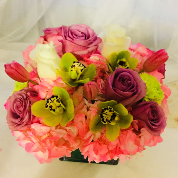 Pink and purple rose bouquet with green orchids in a black container