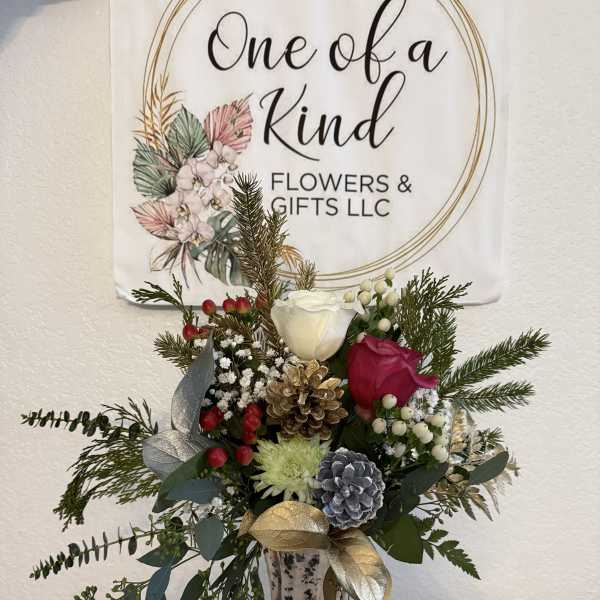 Holiday bouquet in a glass vase with roses, pinecones, and evergreen sprigs