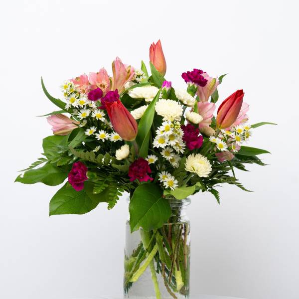 Mixed bouquet of pink and white flowers in a clear glass vase