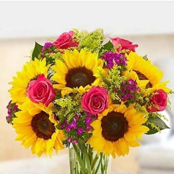 Bouquet of sunflowers and pink roses in a clear glass vase