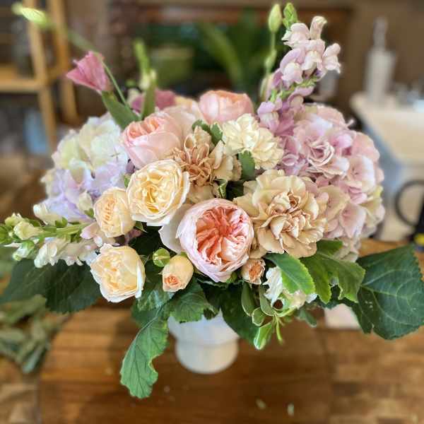 Pastel bouquet of roses, carnations, and hydrangeas in a white vase
