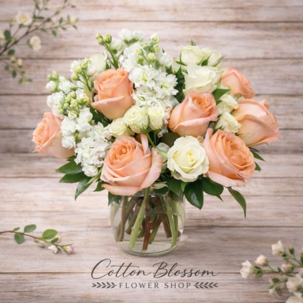 Peach and white roses arranged in a clear glass vase