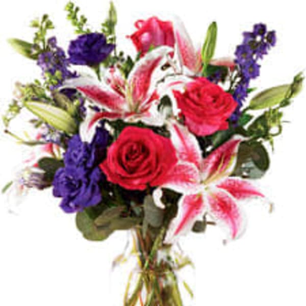 Bouquet of red roses, pink lilies, and purple flowers in a glass vase