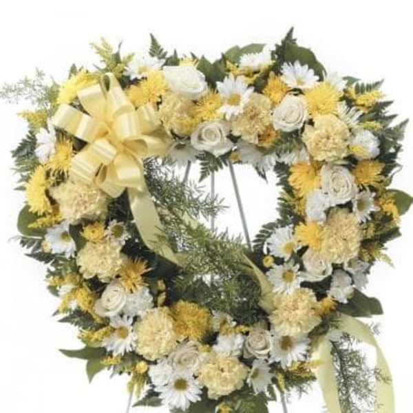 Heart-shaped floral wreath with yellow and white flowers on an easel