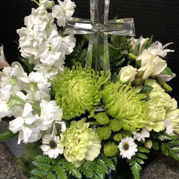White and green floral arrangement with a clear glass cross centerpiece