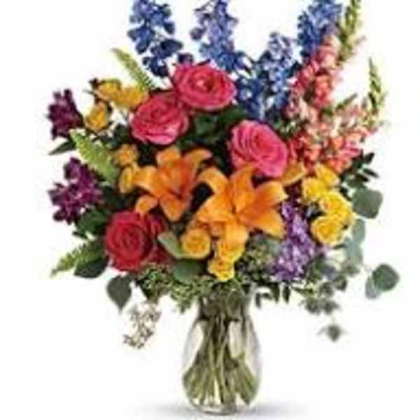 Colorful mixed bouquet with roses, lilies, and snapdragons in a glass vase