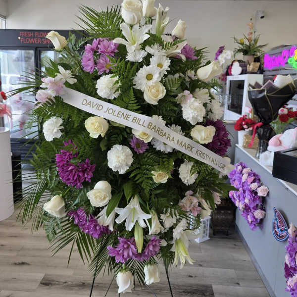 Large standing floral spray with white roses, lilies, and purple daisies