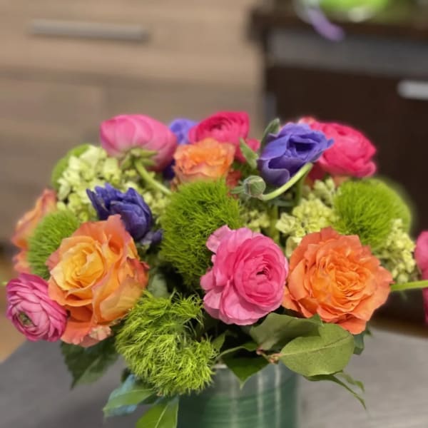 Colorful bouquet of ranunculus in a green vase