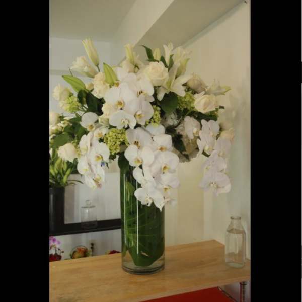 White orchid and lily arrangement in a tall glass vase