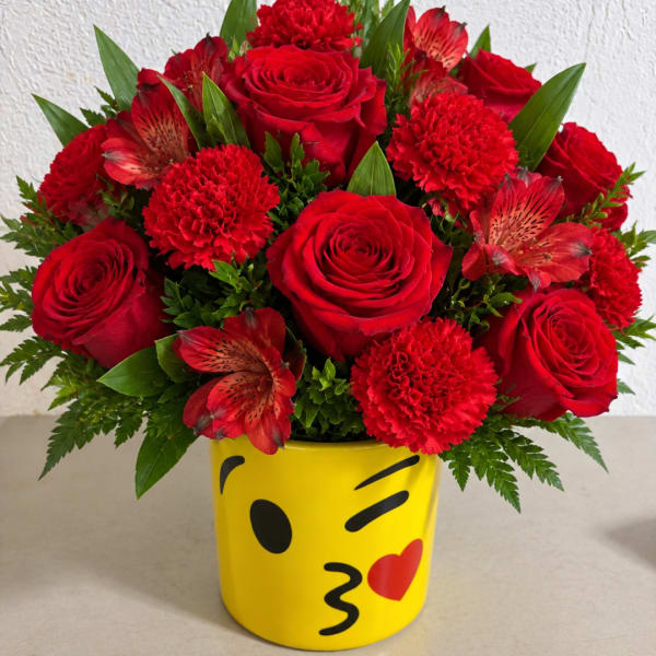 Red roses and carnations in a yellow emoji mug vase