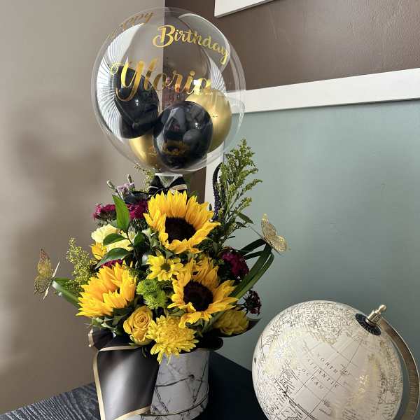 Sunflower bouquet with a birthday balloon in a marble vase