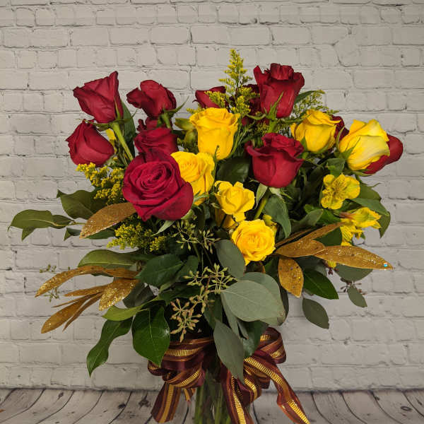 Bouquet of red and yellow roses in a glass vase with ribbon