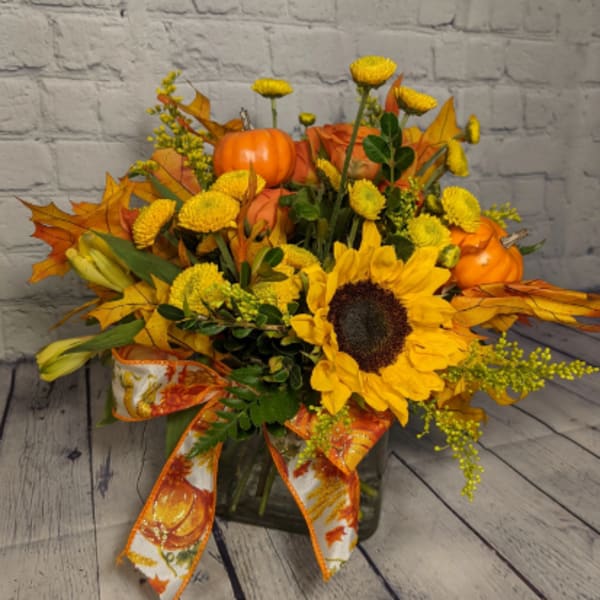 Sunflower and pumpkin arrangement in a glass vase with orange ribbon