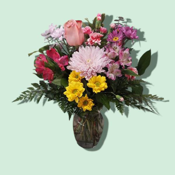 Mixed pink and yellow flowers arranged in a glass vase