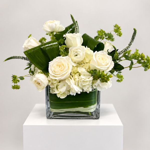 White roses and hydrangeas arranged in a square glass vase