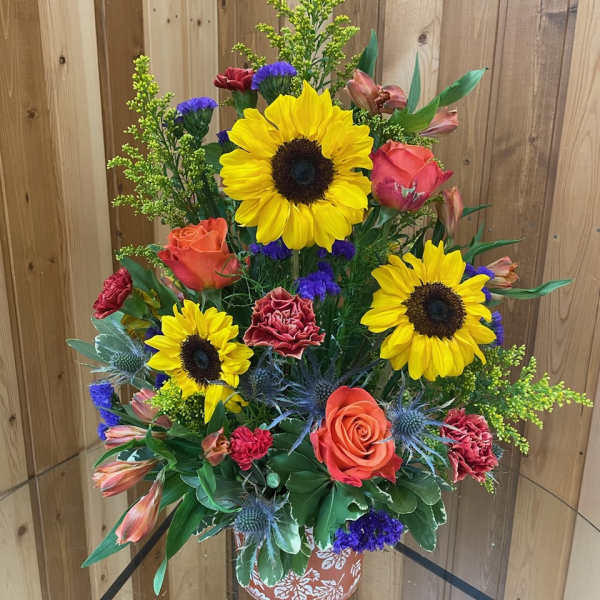 Tall mixed bouquet with sunflowers, roses, and carnations in a decorative vase