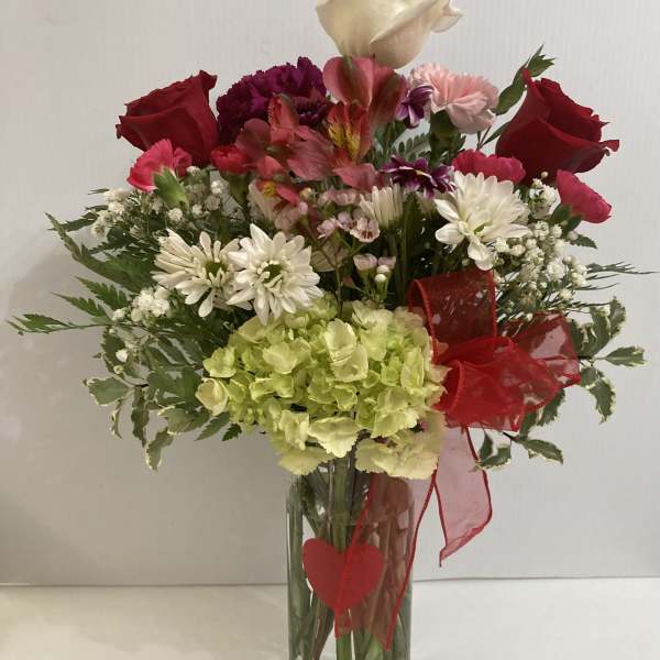 Mixed bouquet in a clear glass vase with red roses and white daisies