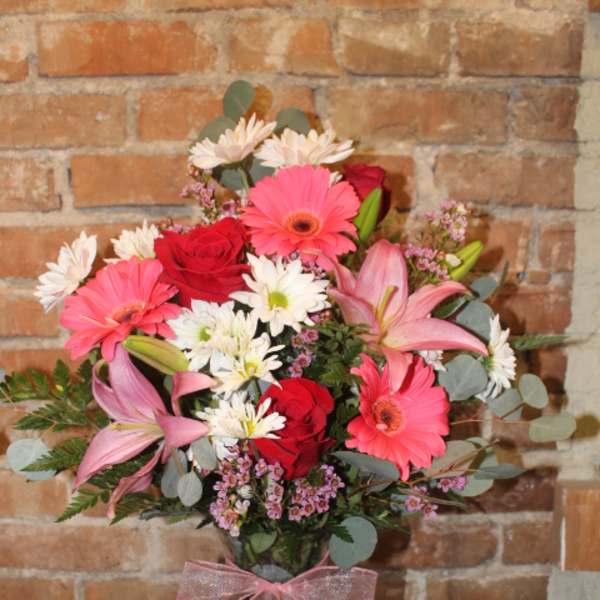 Pink and red mixed bouquet in a glass vase with a ribbon