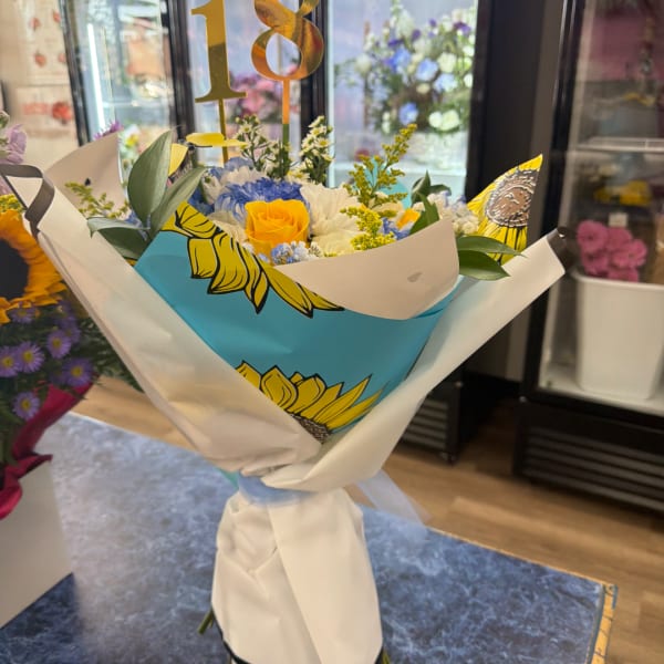 Bouquet of yellow and blue flowers wrapped in white paper